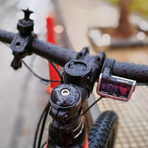 Detailed view of wet bicycle handlebars with raindrops, showcasing outdoor urban cycling in rainy weather.